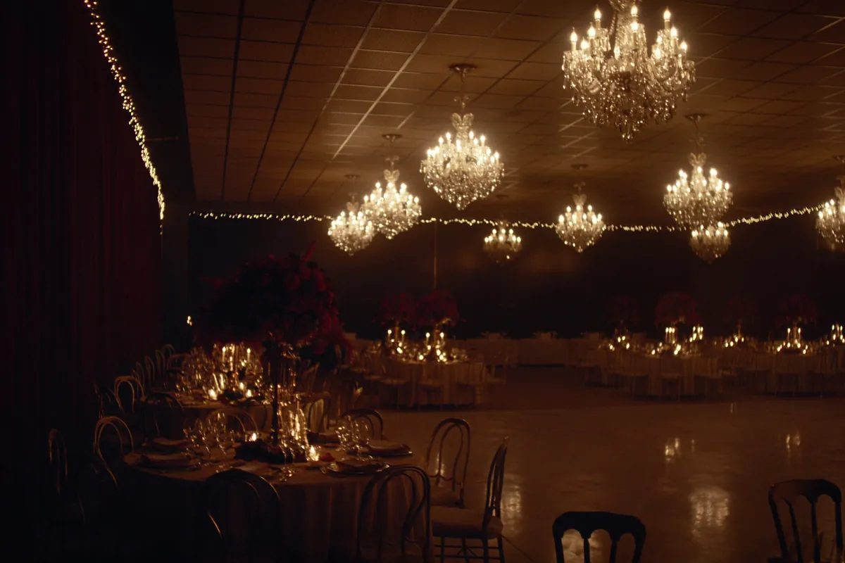 Salón principal de Villa Aurelia iluminado de noche con arañas de cristal encendidas y mesas listas